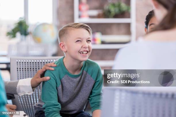 elementary age schoolboy talks with group of kids - child psychologist stock pictures, royalty-free photos & images