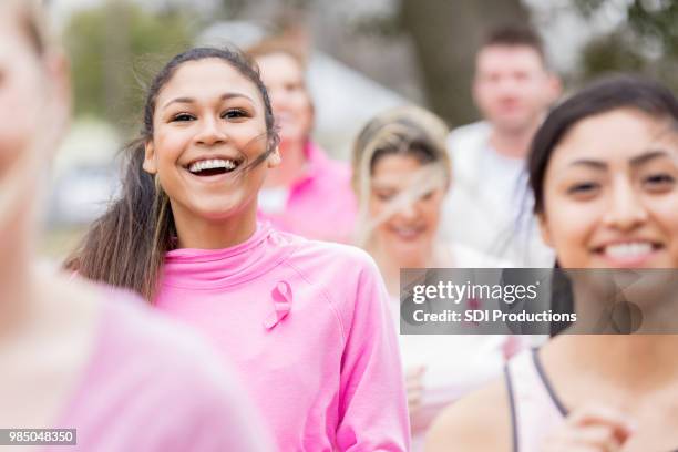 beautiful young women run in charity race - pink ribbon stock pictures, royalty-free photos & images