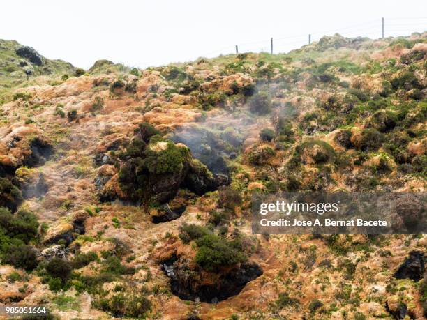 volcanic fumaroles with holes between the rocks issuing gases, surrounded with mosses and plants. terceira island in the azores islands, portugal. - estratovulcão - fotografias e filmes do acervo