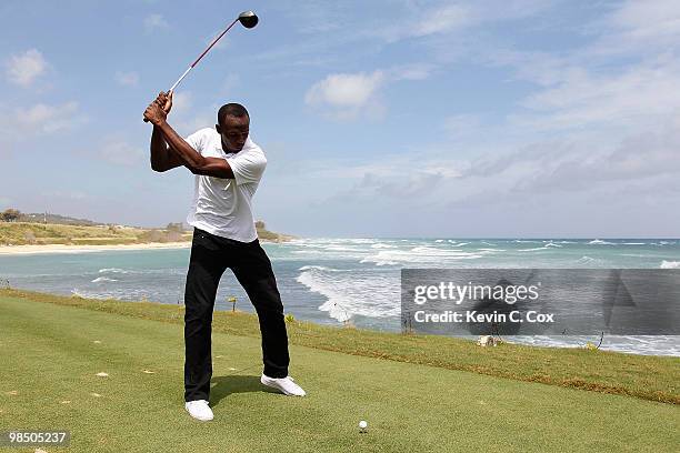 Usain Bolt tees up a golf ball as he drives it into the Caribbean Sea during the quarterfinal matches of The Mojo 6 Jamaica LPGA Invitational at...