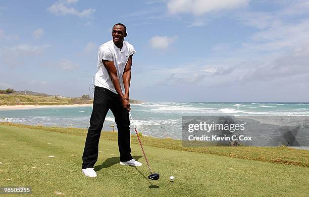 Usain Bolt tees up a golf ball as he drives it into the Caribbean Sea during the quarterfinal matches of The Mojo 6 Jamaica LPGA Invitational at...