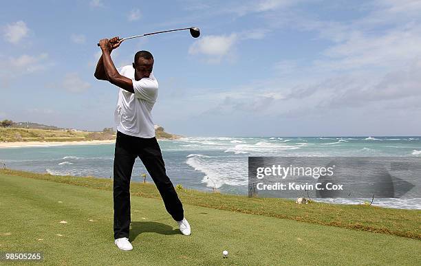 Usain Bolt tees up a golf ball as he drives it into the Caribbean Sea during the quarterfinal matches of The Mojo 6 Jamaica LPGA Invitational at...