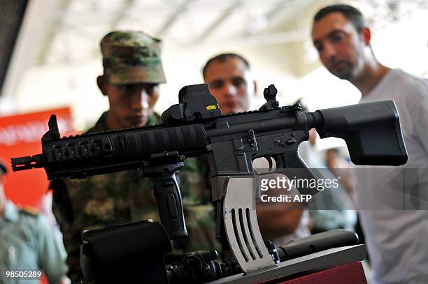 People watch a rifle Colt AR-15 at the 2010 Expodefensa fair in Cali, Colombia on April 16, 2010. AFP PHOTO/Luis ROBAYO