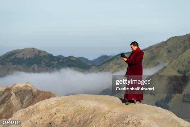 unidentified monk take a photo on a top of mount bromo at bromo tengger semeru national park, east java, of indonesia. - shaifulzamri fotografías e imágenes de stock