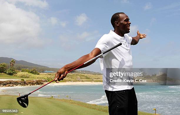 Usain Bolt tees up a golf ball as he drives it into the Caribbean Sea during the quarterfinal matches of The Mojo 6 Jamaica LPGA Invitational at...