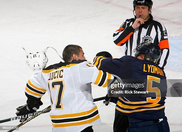 Milan Lucic of the Boston Bruins and Toni Lydman of the Buffalo Sabres throw punches as referee Don O'Halloran blows his whistle in Game One of the...