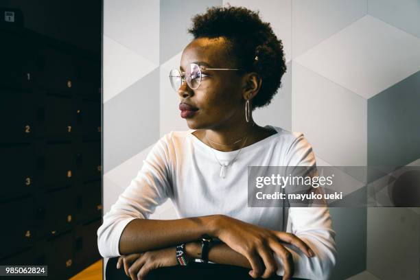 portrait of young woman who sits down on a chair - ファッション stock pictures, royalty-free photos & images