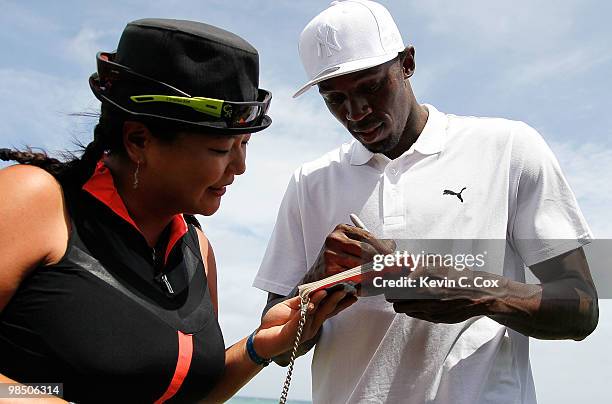 Usain Bolt signs an autograph for Christina Kim of the United States during the semifinal matches of The Mojo 6 Jamaica LPGA Invitational at Cinnamon...