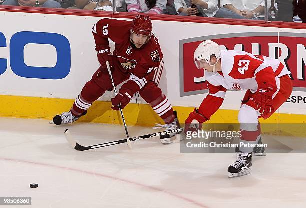 Matthew Lombardi of the Phoenix Coyotes passes the puck under pressure from Darren Helm of the Detroit Red Wings in Game One of the Western...