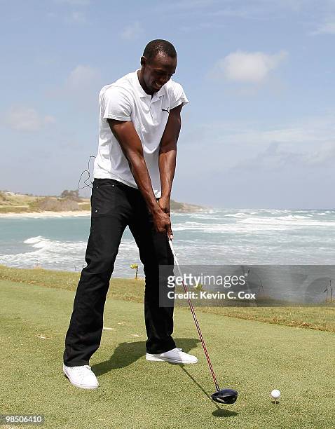 Usain Bolt tees up a golf ball as he drives it into the Caribbean Sea during the quarterfinal matches of The Mojo 6 Jamaica LPGA Invitational at...