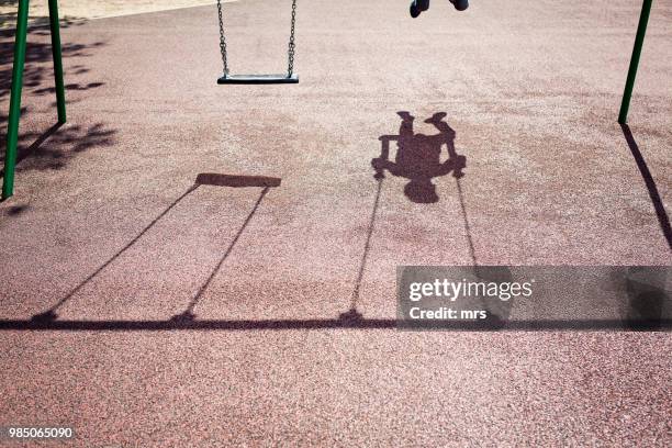 shadow of a child on a playground swing - kids playground stock-fotos und bilder