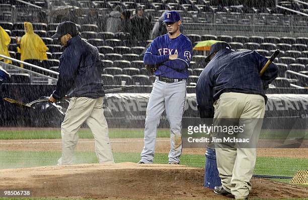 Michael Young of the Texas Rangers watches the ground crew work on the pitchers mound prior to a rain delay against the New York Yankees on April 16,...