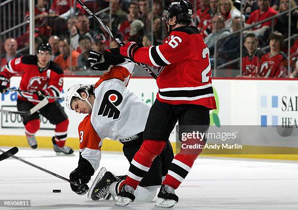 Daniel Carcillo of the Philadelphia Flyers is bent over backwards onto the ice on a hard check by Patrik Elias of the New Jersey Devils in Game Two...