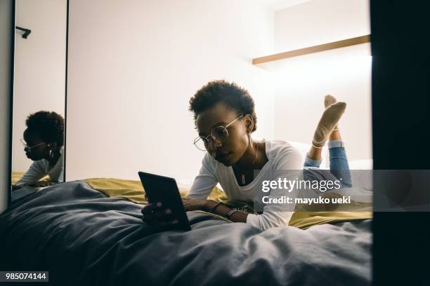 young woman who is relaxed on a bed - ファッション stock pictures, royalty-free photos & images