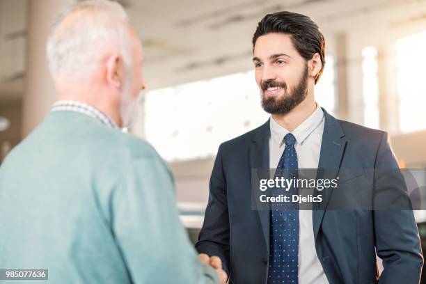 happy young salesman shaking hands with male mature costumer. - costumer stock pictures, royalty-free photos & images