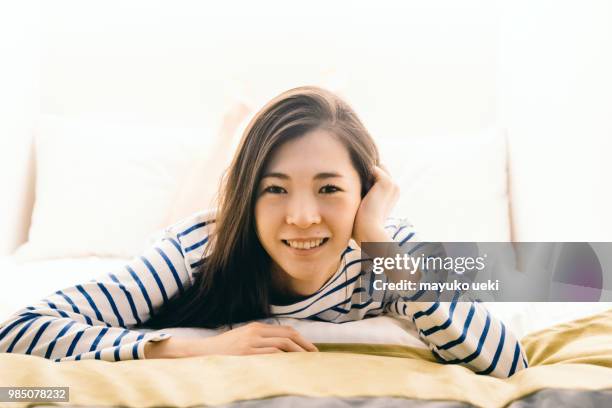 young woman who is relaxed on a bed - ファッション stock pictures, royalty-free photos & images