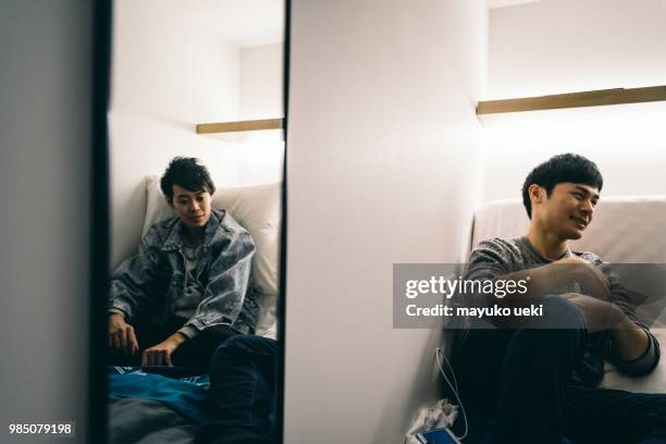 young men having a pleasant chat on a bed - ファッション stock pictures, royalty-free photos & images