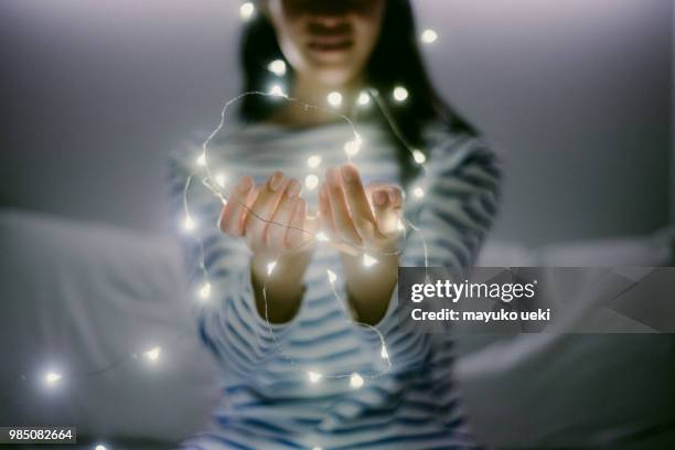 joven teniendo un montón de pequeñas luces con las manos - ライトアップ fotografías e imágenes de stock