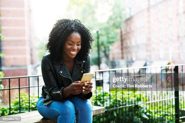 woman using smart phone on bench. - park bench stock pictures, royalty-free photos & images