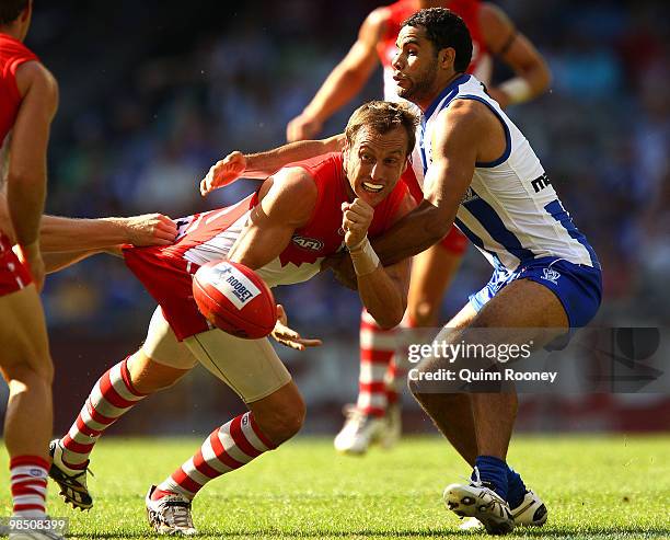 Jude Bolton of the Swans handballs whilst being tackled by Daniel Wells of the Kangaroos during the round four AFL match between the North Melbourne...