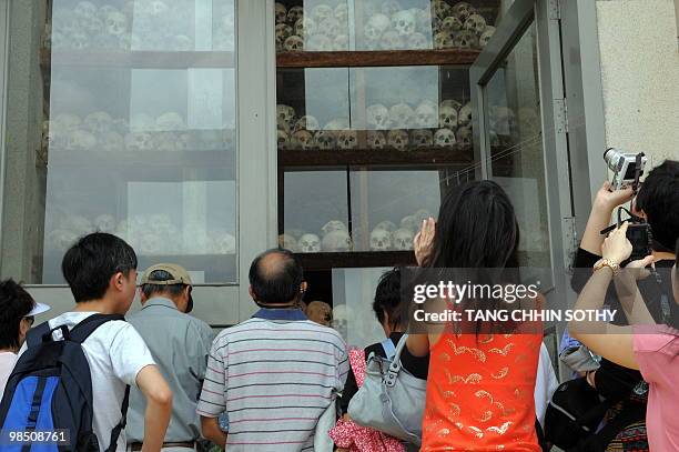 Foreign tourists take pictures of skulls displayed at the Choeung Ek killing fields memorial in Phnom Penh on April 17, 2010. Cambodia marked the...