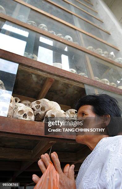 Cambodian woman prays in front of skulls displayed at the Choeung Ek killing fields memorial in Phnom Penh on April 17, 2010. Cambodia marked the...