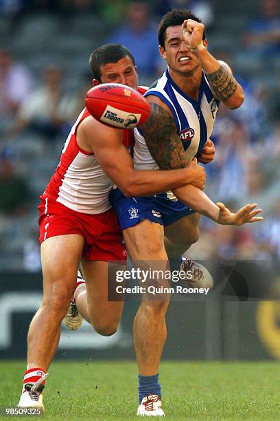 Aaron Edwards of the Kangaroos handballs whilst being tackled by Jarred Moore of the Swans during the round four AFL match between the North...