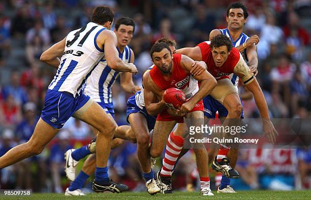 Rhyce Shaw of the Swans handballs whilst being tackled during the round four AFL match between the North Melbourne Kangaroos and the Sydney Swans at...