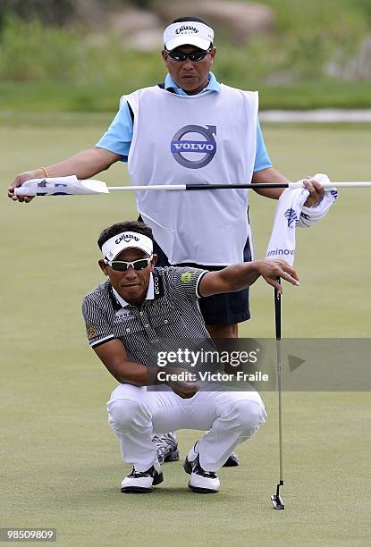 Thongchai Jaidee of Thailand lines up a putt with his caddie on the 2nd green during the Round Three of the Volvo China Open on April 17, 2010 in...