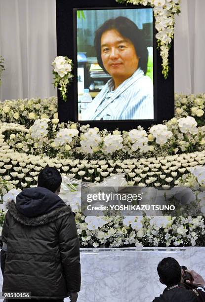 Journalists look up at a portrait of slain Japanese journalist Hiroyuki Muramoto on an altar before starting his wake at a funeral hall in Tokyo on...