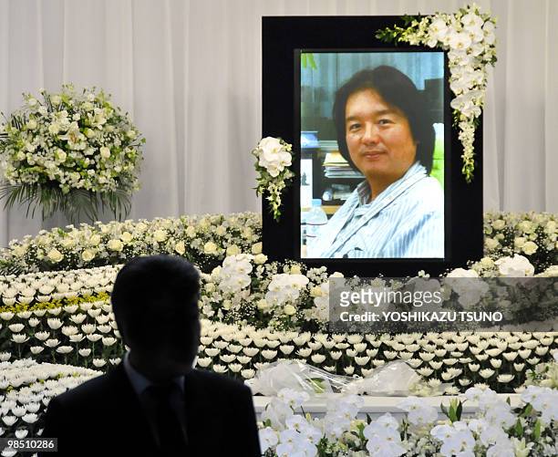 Man walks past a portrait of slain Japanese journalist Hiroyuki Muramoto on an altar before his wake at a funeral hall in Tokyo on April 17, 2010....