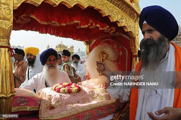 Indian Sikh priest Sukhjinder Singh walks beside The Guru Granth Sahib escorted by Sikh devotees known as Punj Pyara during a procession from Sri...