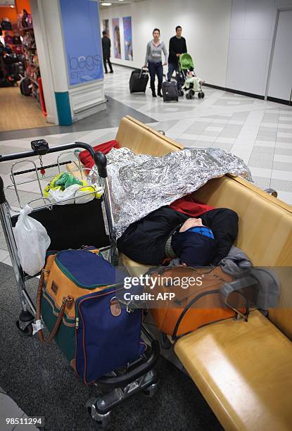 Man sleeps under a foil blanket at London Gatwick Airport in Hurley, in West Sussex, on April 17,2010. Britain has extended a ban on most flights in...