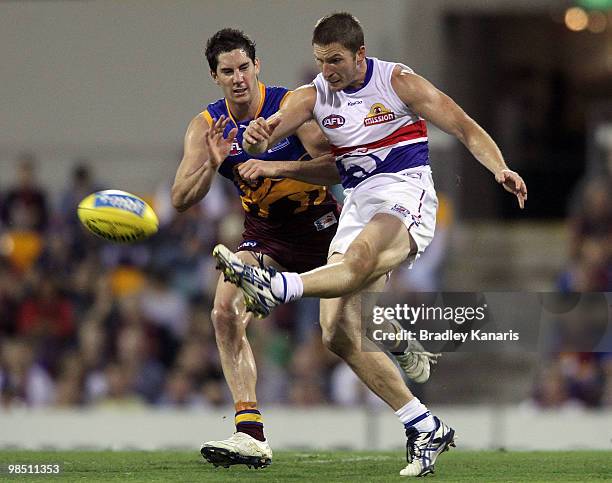 Lindsay Gilbee of the Bulldogs kicks the ball as he is challenged by the Lions defence during the round four AFL match between the Brisbane Lions and...