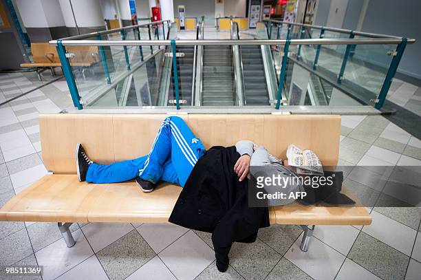 Man sleeps at London Gatwick Airport in Hurley, West Sussex, on April 17, 2010. Britain has extended a ban on most flights in its airspace until 1:00...