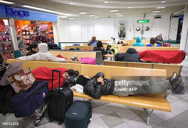Passengers sleep at London Gatwick Airport in Hurley, West Sussex, on April 17, 2010. Britain has extended a ban on most flights in its airspace...
