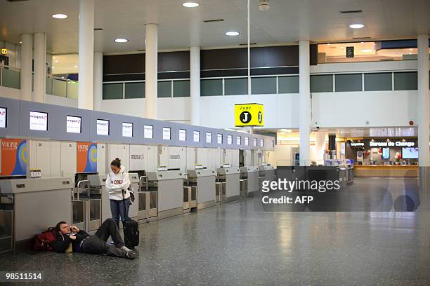 Couple wait near deserted check-in desks at London Gatwick Airport in Hurley, West Sussex on April 17, 2010. Britain has extended a ban on most...
