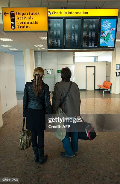 Couple look at the departures board at London Gatwick Airport in Hurley in West Sussex, on April 17, 2010. Britain has extended a ban on most flights...