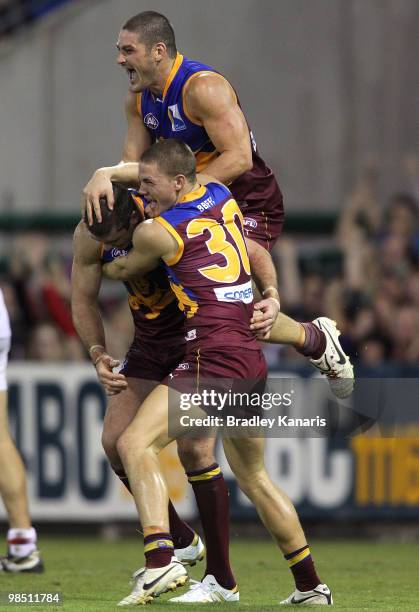 Jonathan Brown of the Lions celebrates with team mates Brendan Fevola and Jack Redden after scoring a goal during the round four AFL match between...