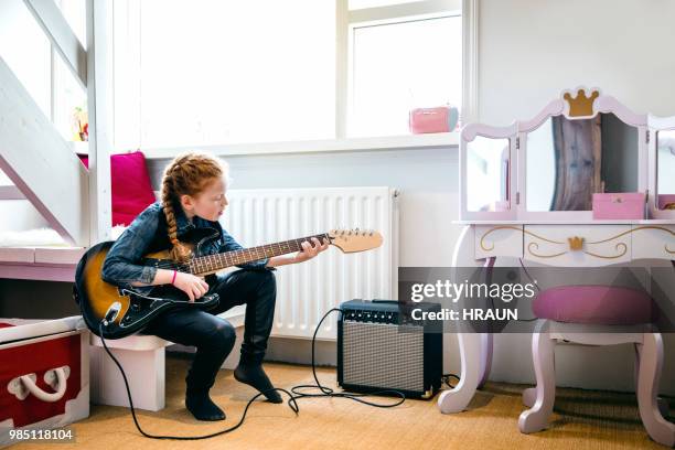 red hair girl playing electric guitar in her bedroom. - boom for real stock pictures, royalty-free photos & images