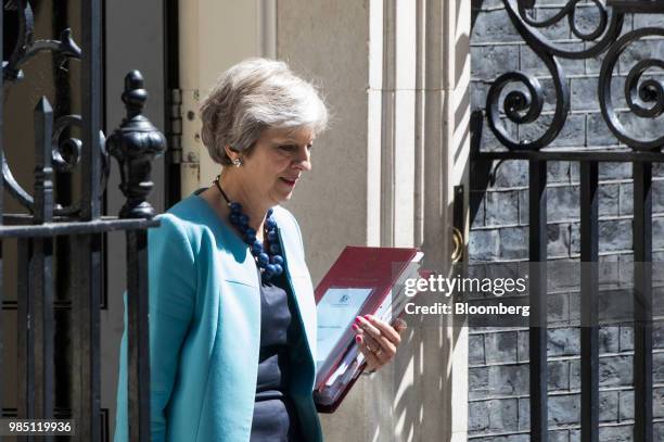 Theresa May, U.K. Primer minister, carries a document folder as she departs number 10 Downing Street to attend a weekly questions and answers session...