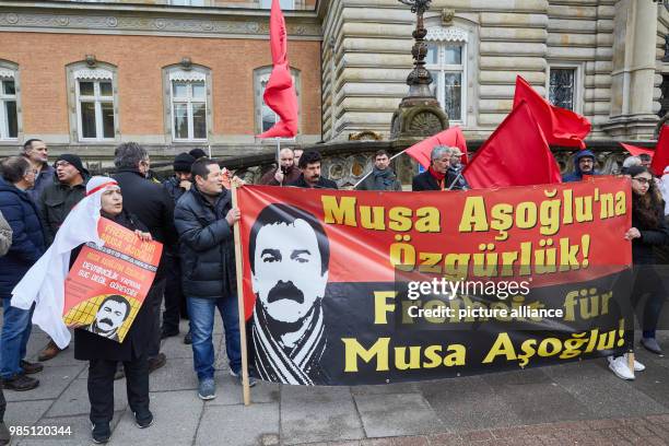 Protesters standing in front of the Criminal Justice Building holding red flags and banners with the text "Freedom for Musa Asoglu!" in Hamburg,...