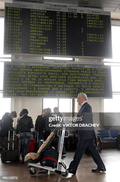 Man walks in front of a departure board displaying a list of cancelled flights at the international airport outside Minsk on April 17, 2010. Air...