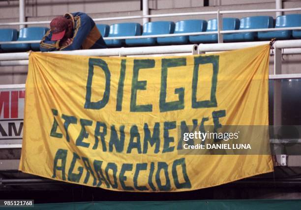 An unidentifed fan of the Argentina football club Boca Juniors leans against a sign that translates to: "Diego, We are eternally grateful," in...