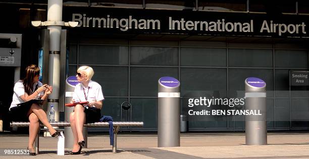 Members of airport staff sit outside a deserted terminal at the Birmingham International Airport in Birmingham, central England, on April 17, 2010....