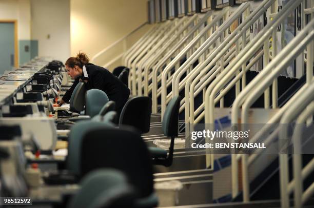 Member of airport staff is seen among deserted check-in desks at the Birmingham International Airport in Birmingham, central England, on April 17,...