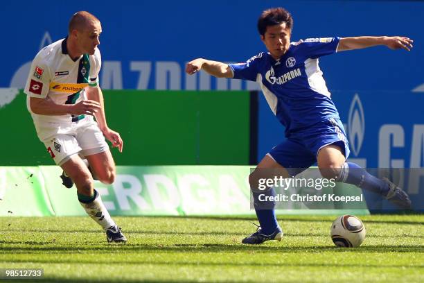 Filip Daems of Gladbach challenges Hao Junmin of Schalke during the Bundesliga match between FC Schalke 04 and Borussia Moenchengladbach at the...