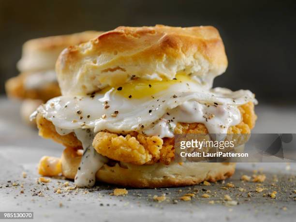 fried chicken sandwich with a fried egg,sausage gravy on a biscuit - southern food stock pictures, royalty-free photos & images