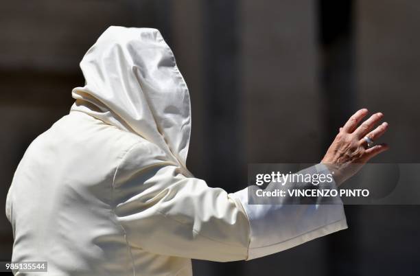 Gust of wind blows Pope Francis's mantle as he waves to people in St. Peters square at the Vatican at the end of his weekly general audience on June...