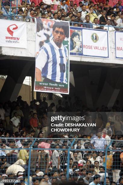 Giant banner of Argentina's national team coach and former football star Diego Armando Maradona is seen hung from the rafters as Indian spectators...